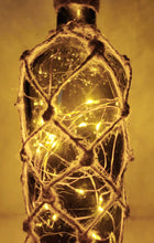 Load image into Gallery viewer, Braided Green Glass Bottle Lamp - Braided Green Glass Bottle Lamp - Lit up Green glass standard wine bottle with jute twine braiding in a diamond pattern. Jute twine around the bottom and neck f the bottle. Cork LED lights
