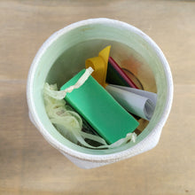 Load image into Gallery viewer, white jar with contents inside showing a green bar of soap and a yellow organza bag