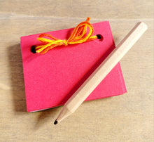 Load image into Gallery viewer, dark pink mini scrapbook tied with yellow embroidery thread. A short light brown pencil on the top