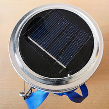 Load image into Gallery viewer, Small round device with a solar panel on a beige background