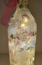 Load image into Gallery viewer, Decoupage Fairy bottle lamp - Lit up standard wine bottle with Fairy and flower butterfly detailing. Pink organza ribbon tied around the neck of the bottle. Cork LED lights