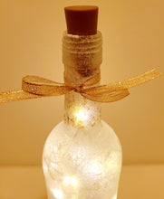 Load image into Gallery viewer, Lit up wine bottle with gold ribbon tied around the neck. Brown plastic cork