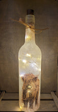 Load image into Gallery viewer, Lit up wine bottl with highland cow detail near the bottom. Gold ribbon tied around the neck of the bottle. ork LED lights