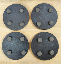 Load image into Gallery viewer, Four round, black slate coasters with four protective pads on each one on their undersides
