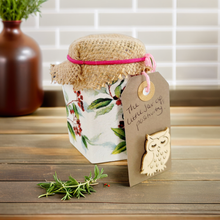 Load image into Gallery viewer, white painted jar with green leaf and red berry detail. Brown hessian lid with pink elastic band, Light brown luggage tag with owl detail