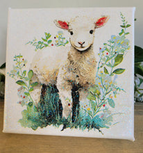 Load image into Gallery viewer, Canvas print of a lamb surrounded by flowers and leaves on a wooden surface.