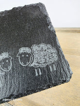 Load image into Gallery viewer, Black stone with engraved sheep design on a wooden surface