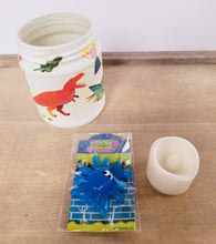 Load image into Gallery viewer, white painted jar with Dinosaur detail. A sticky blue monster toy and cream flameless plastic candle