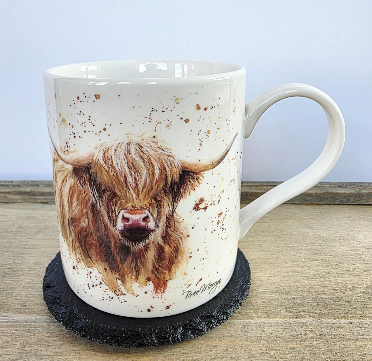 Mug with a highland cow design on a wooden surface