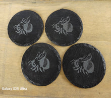 Load image into Gallery viewer, Four black coasters with a engraved bee design on a wooden surface
