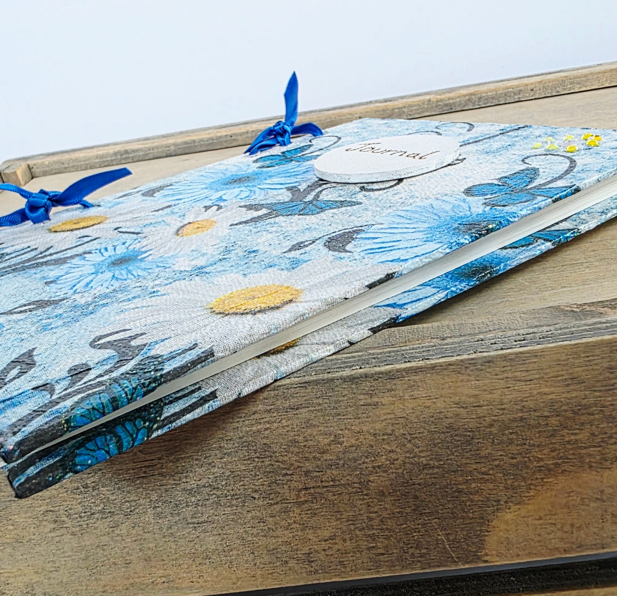 Notebook with blue floral and butterfly design on cover and lined pages. Showing side edge