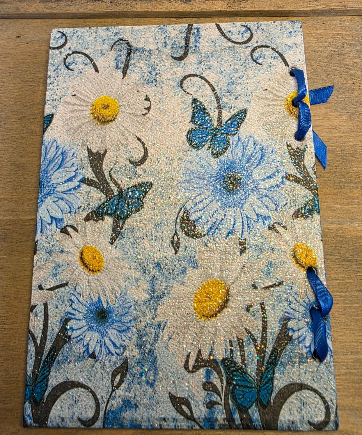 decoupage Journal with blue floral and butterfly  design and blue ribbons on a wooden surface. back cover