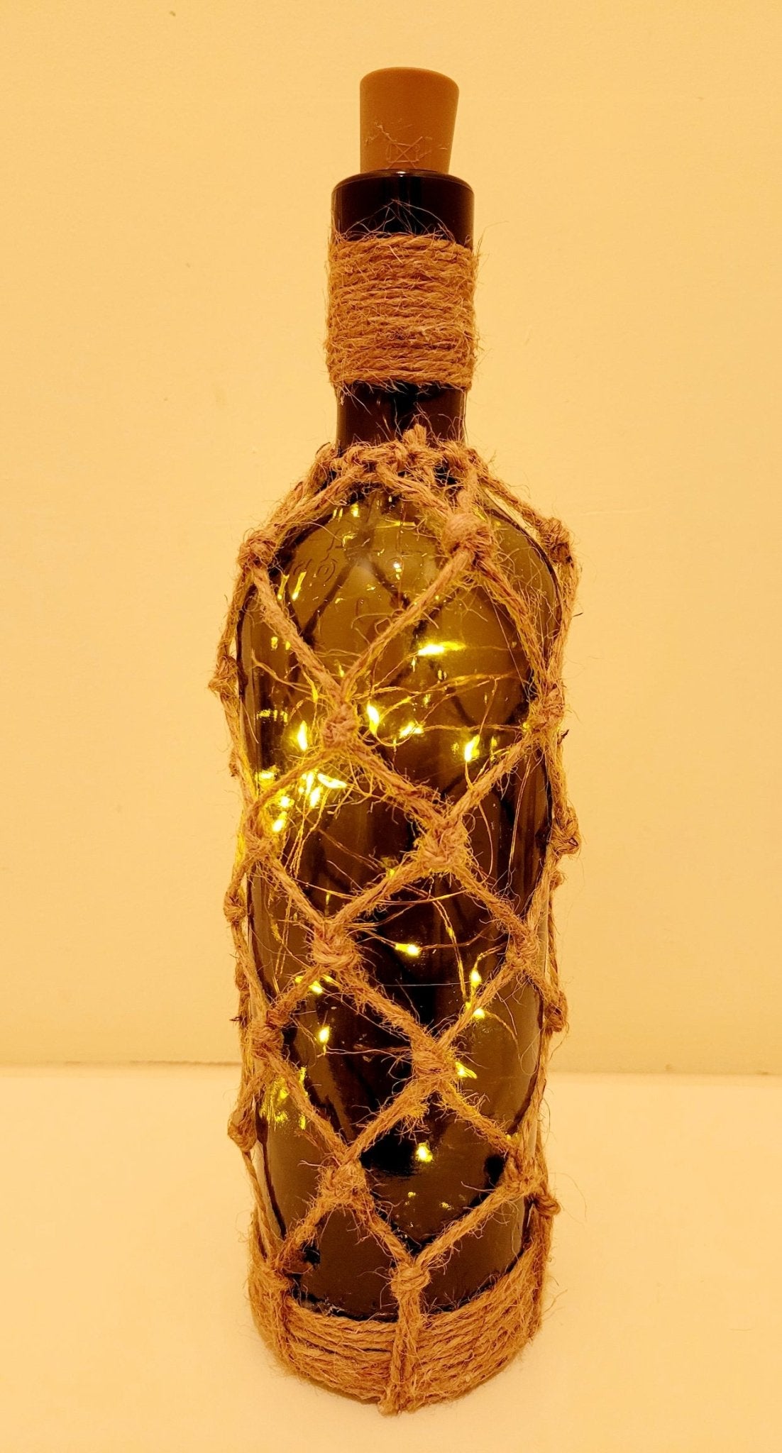 braided jute string bottle with green glass and LED lights. Brown plastic cork