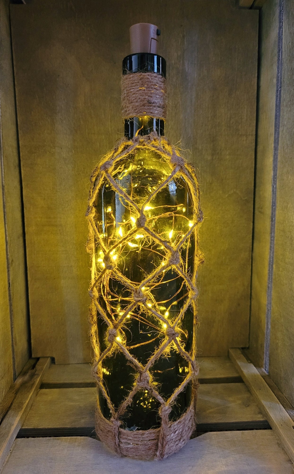braided jute string bottle with green glass and LED lights. Brown plastic cork