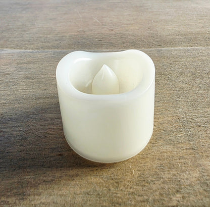 White flameless candle on a wooden surface. Not switched on.