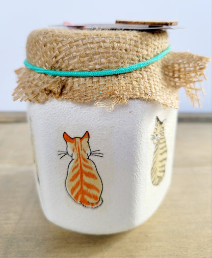 white jar with a marmalade cat and tabby cat looking over its shoulder. Brown hessian lid secured with green elastic band
