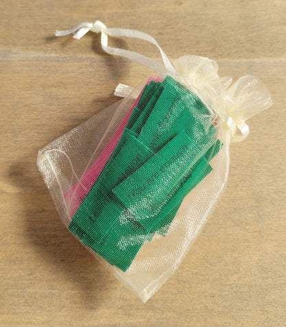 Pale yellow organza bag containing green and pink paper quotes