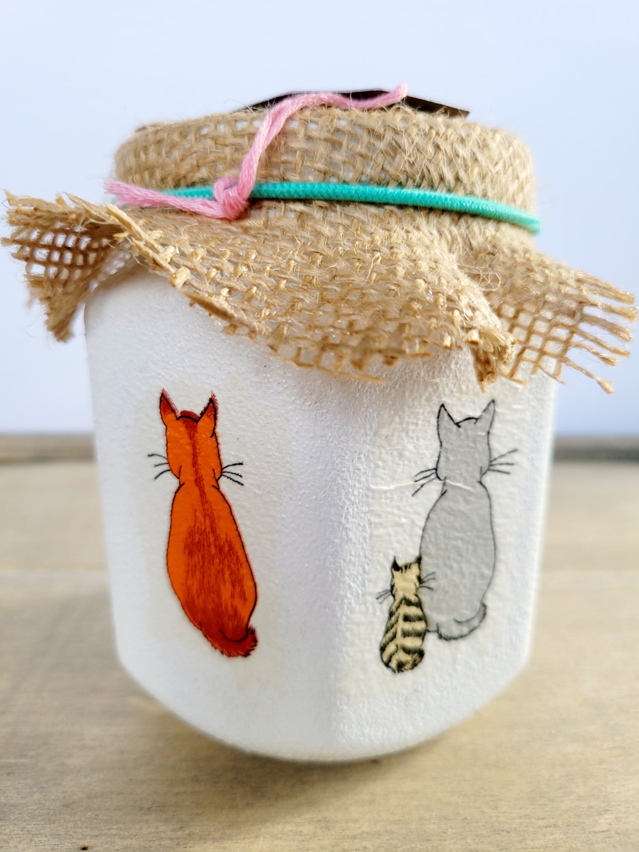white jar with orange and grey cat detail Brown hessian lid with green elastic