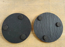Load image into Gallery viewer, Two black circular coasters with three protective pads on the underside on each.
