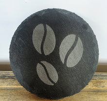 Load image into Gallery viewer, Round black slate coaster with coffee bean design on a wooden surface
