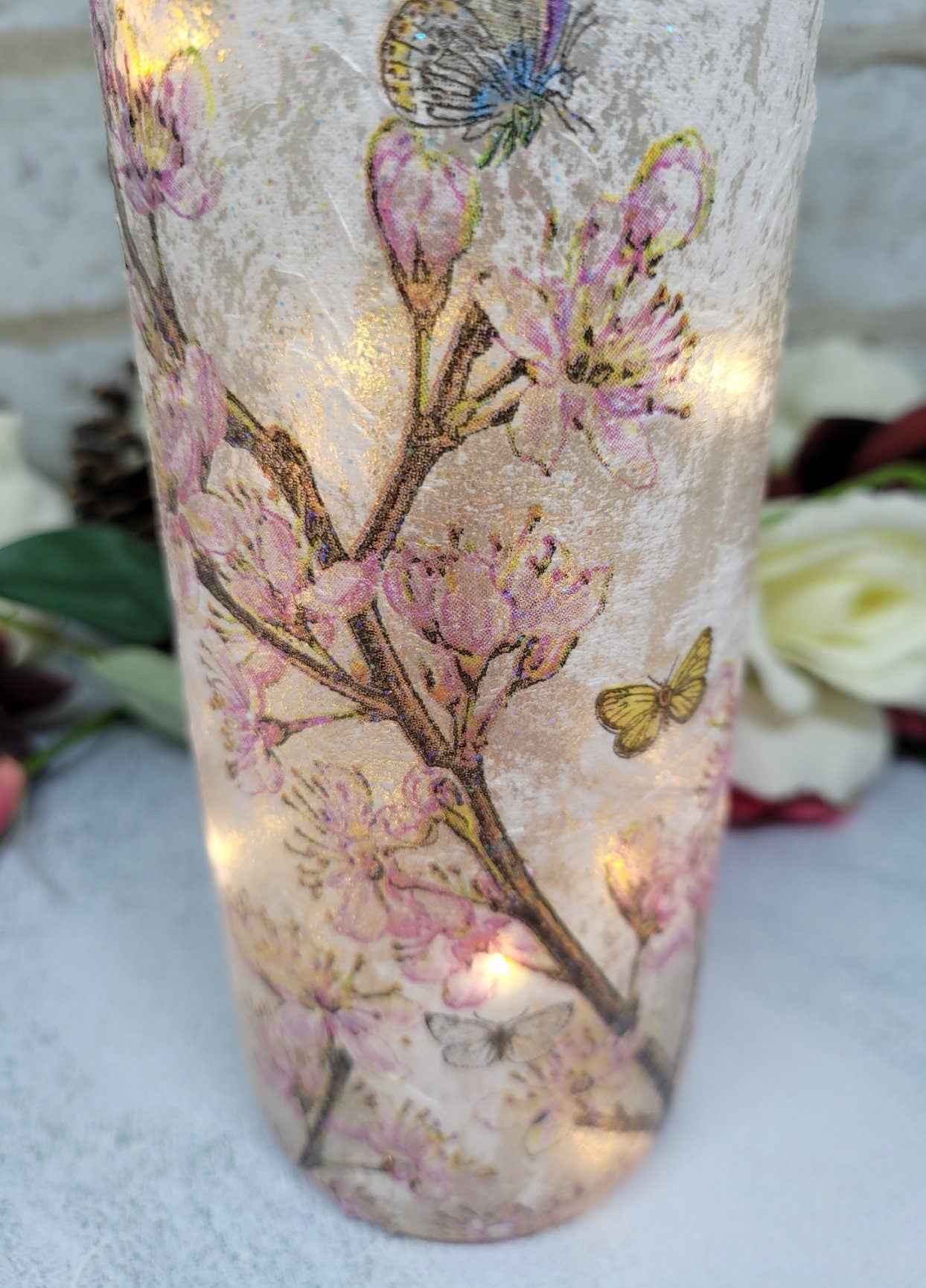 Wine bottle with textured flowers and butterfly design. Shown bottom half of bottle with lit up lights inside
