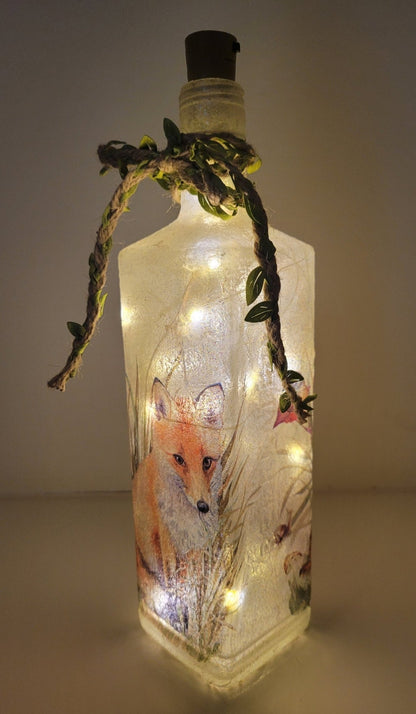 Decoupage Fox Bottle Lamp - Lit up square gin bottle with fox detail and jute twine with leaves wrapped around the neck of the bottle. Cork LED lights