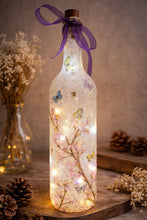 Load image into Gallery viewer, Decorative light-up bottle with floral and butterfly design, surrounded by dried plants and pinecones.
