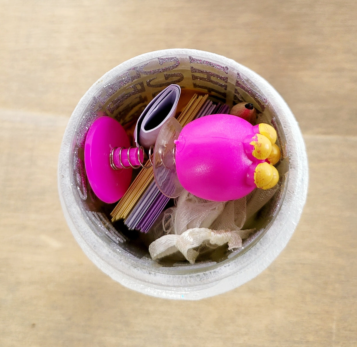 White painted jar with contents inside, pink toy sitting on the top