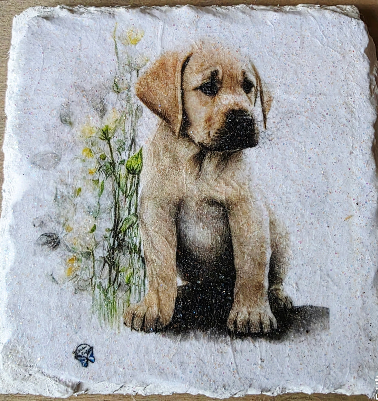 Artistic depiction of a golden labrador puppy surrounded by flowers on a white painted slate coaster