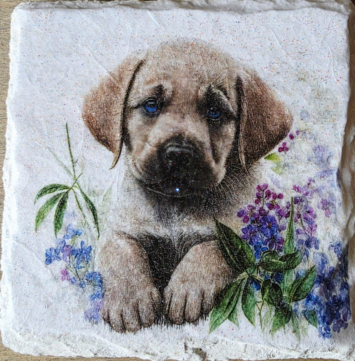 Artistic depiction of a golden labrador puppy surrounded by flowers on a white painted slate coaster