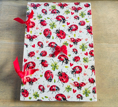 ladybird themed notebbok bound with red ribbon and with  a small red ribbon on the front.