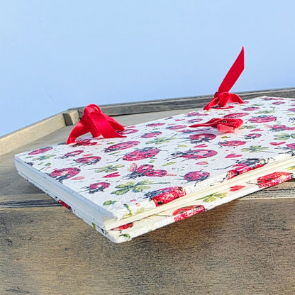 ladybird patterned notebook with red ribbon on a wooden surface