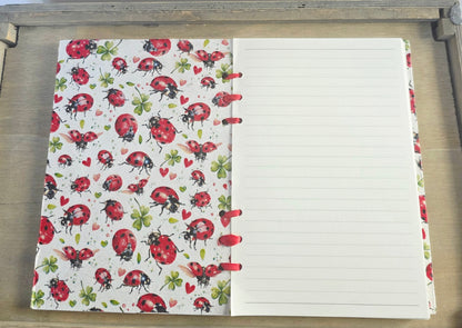 Notebook with ladybug pattern on the cover and lined pages. red ribbon bound