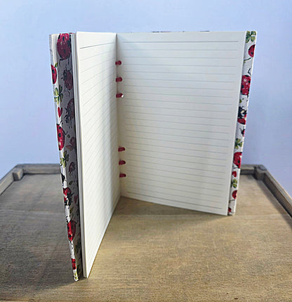 Notebook with ladybird design on the cover and spine, open to a blank page.