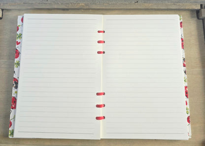 Open notebook with lined pages on a wooden surface. red and white cupboard and red ribbon bound.