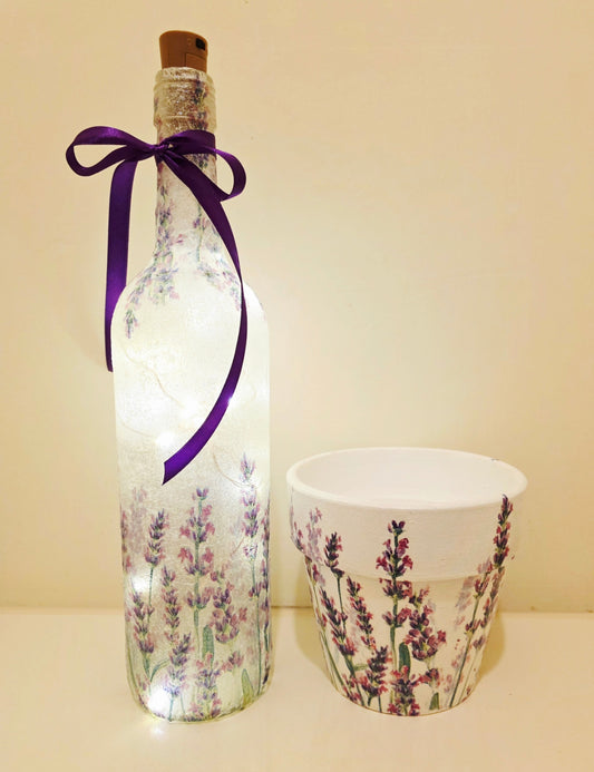 Decorative bottle with lavender design, LED lights and purple ribbon and a matching flowerpot on a plain background