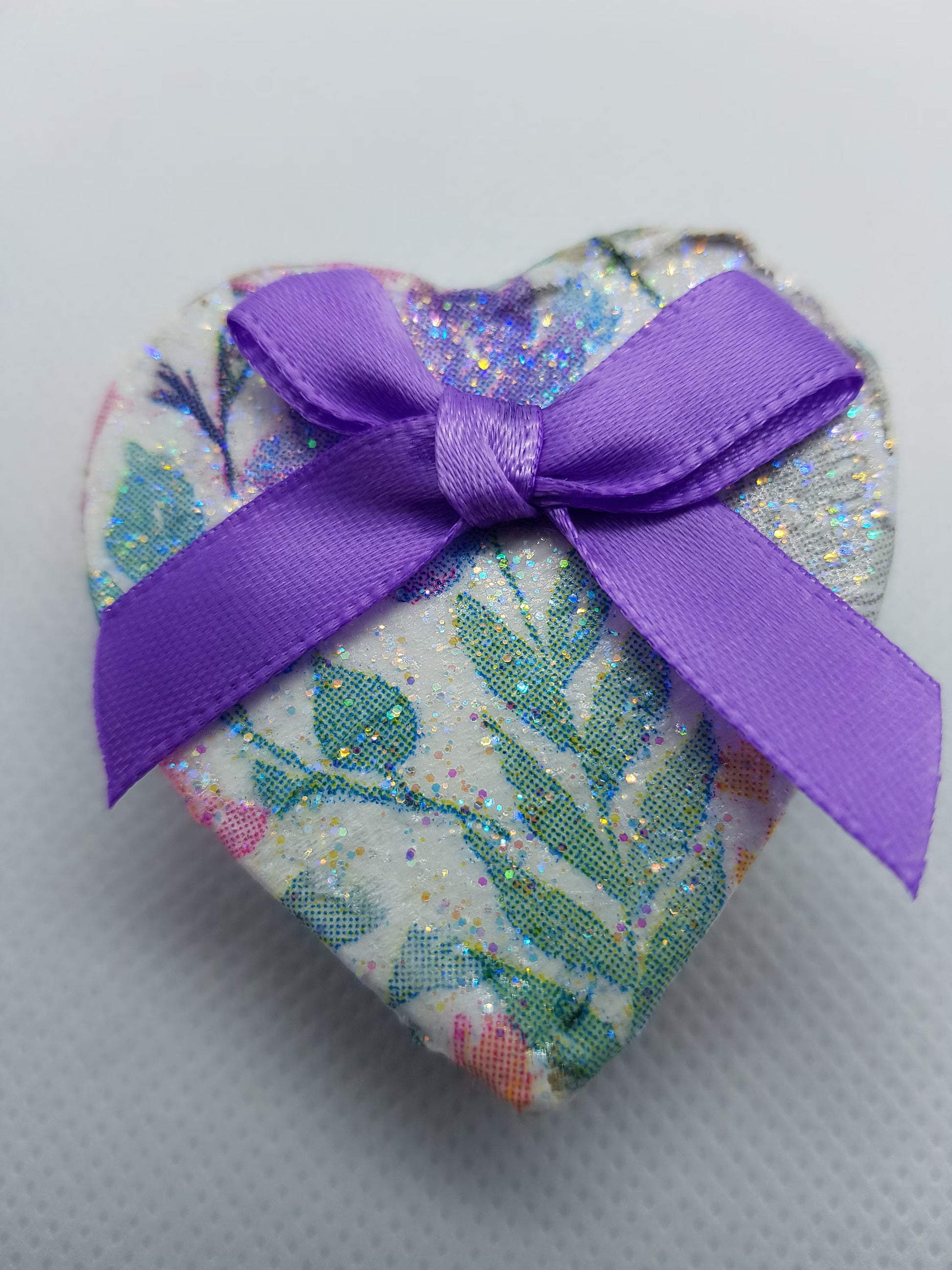 Heart-shaped box with a purple ribbon on a light gray background