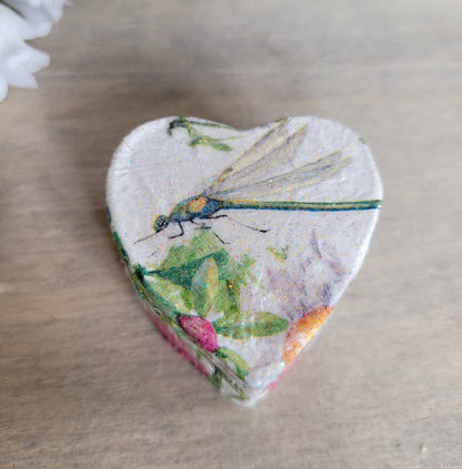 Heart-shaped box with a dragonfly and floral design on a wooden surface