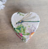 Heart-shaped box with a dragonfly and floral design on a wooden surface