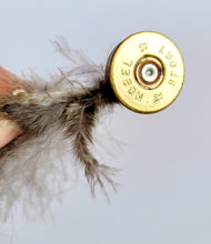 Load image into Gallery viewer, gold coloured shotgun cartridge with small grey feathers in the end
