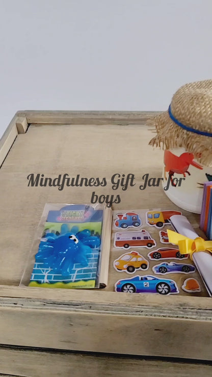 Video of a White painted jar with Dinosuar detail. Hessian lid secured with a blue band, sticker sheet, blue sticky toy, lit up flameless votive candle, white rolled up note secured with yellow ribbon, key ring attached to jar with a green Dinosaur on it. Coloured card scrapbook and short brown pencil, organza bag containing pink and blue quotes