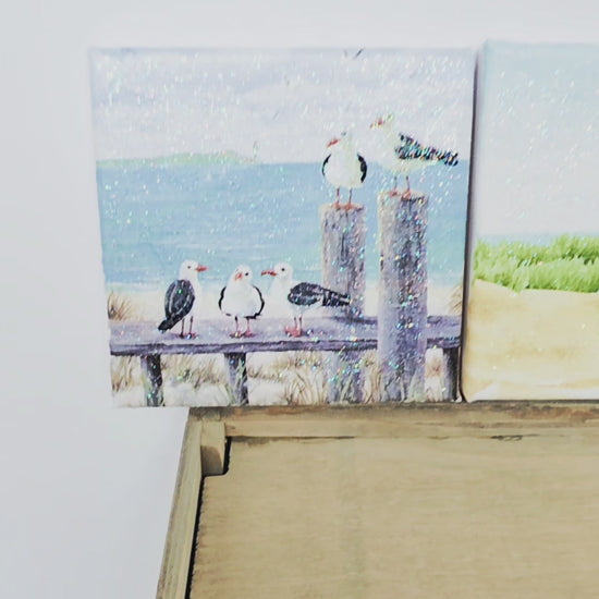 A video of three beach scene canvases - a beach hut, seagulls and a lighthouse. All images a re square