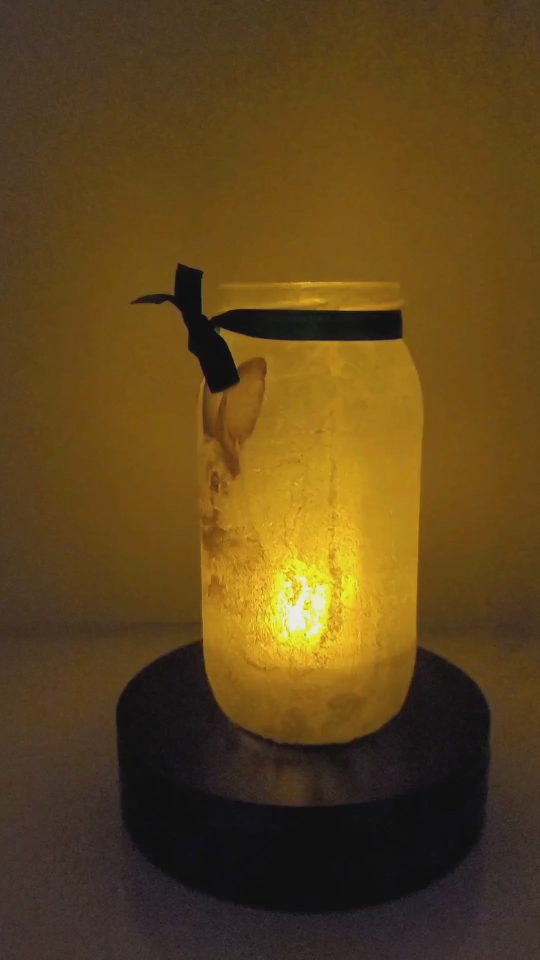 Rotating example of a Lit up glass jar with Hares in the snow detail, flameless candle and green bow