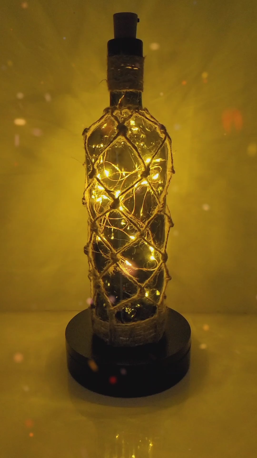 Rotating example of a green glass bottle with jute twine braided all the way down, with LED lights switched on inside