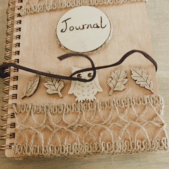 video of a Wooden journal with decorative wooden leaves and owl elements. Burlap jute decoration top and bottom. Faux suede tie