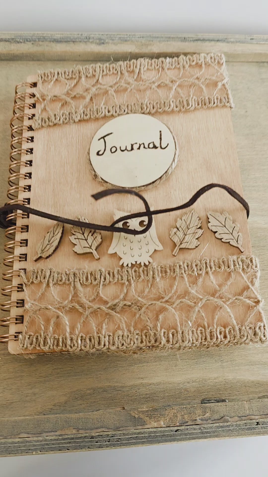video of a Wooden journal with decorative wooden leaves and owl elements. Burlap jute decoration top and bottom. Faux suede tie
