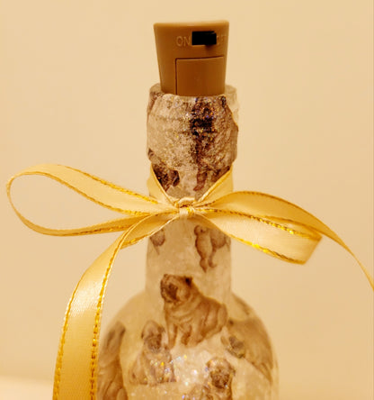 Gold ribbon embellishment around the neck of a wine bottle. Brown cork with black on/off switch