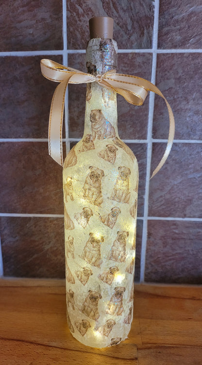 wine bottle decorated with tiny pug dog images. Cork LED lights and gold ribbon embellishment