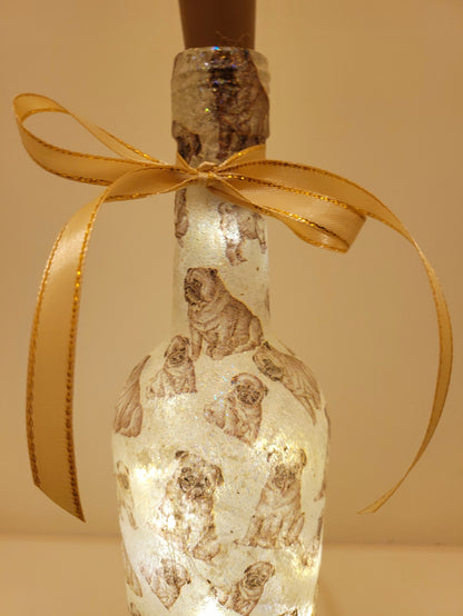 Gold ribbon embellishment around the neck of a wine bottle. Brown cork with on/off switch. Pug detailing on bottle