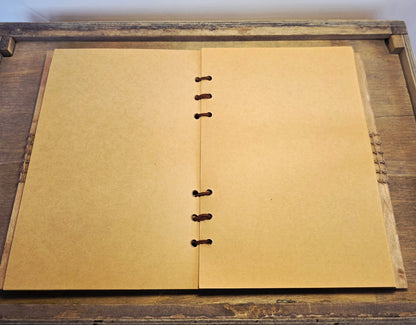 Open notebook with beige pages on a wooden surface